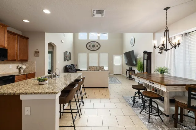 a living room with granite countertop furniture a dining table and a chandelier