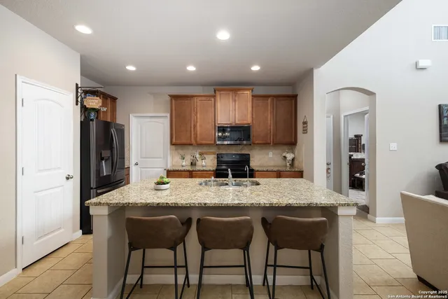 a kitchen with stainless steel appliances granite countertop a table chairs sink refrigerator and cabinets