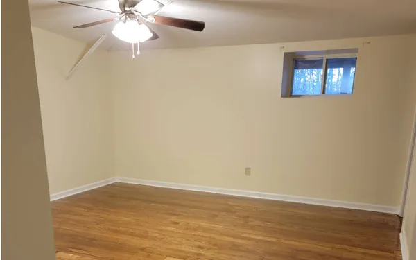 an empty room with wooden floor closet and fan