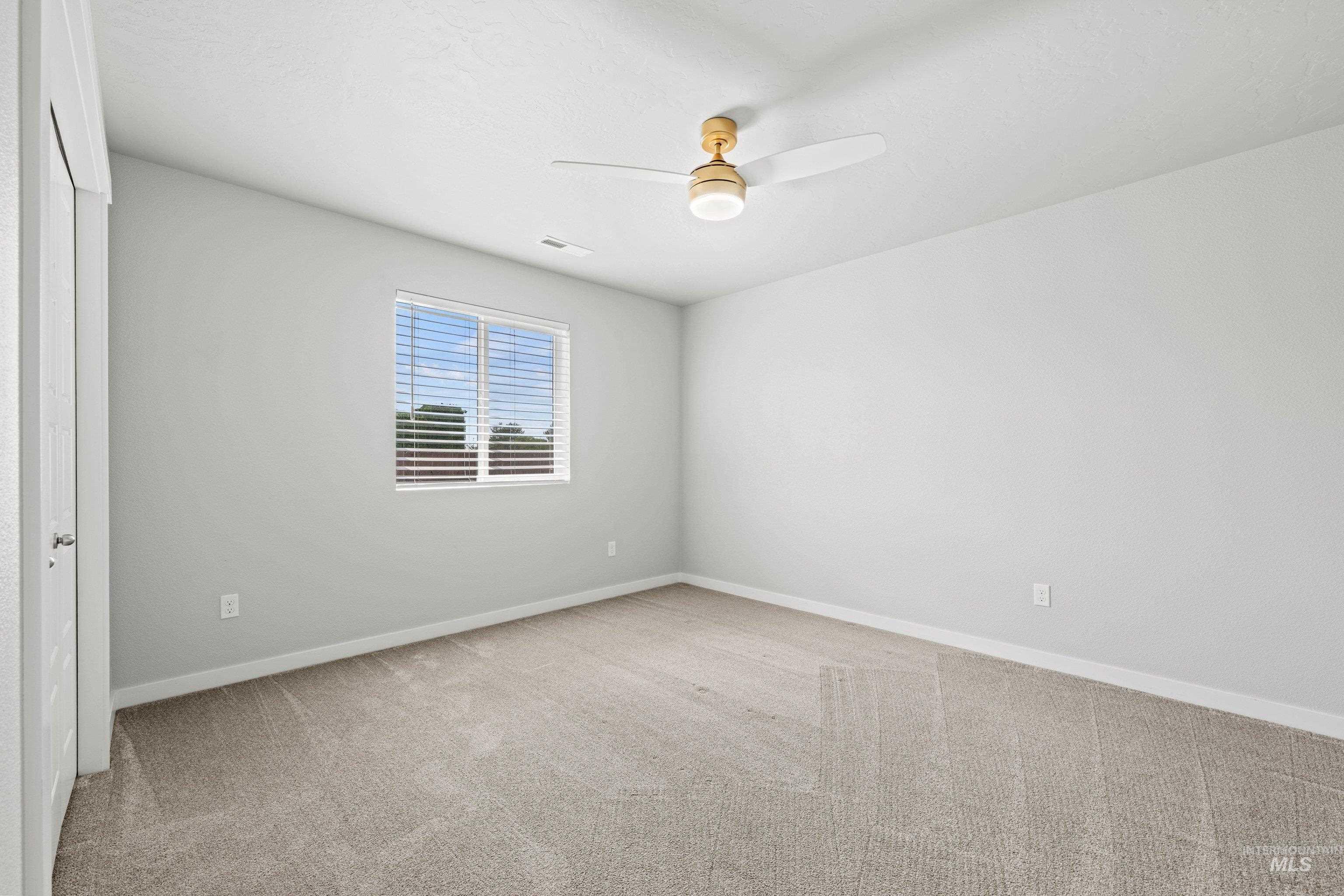 12744 West Fig Street Boise, ID 83713 - Photo 23 of 34 Spacious room featuring light gray walls, plush carpeting, a single window with horizontal blinds, and a ceiling fan with integrated lighting