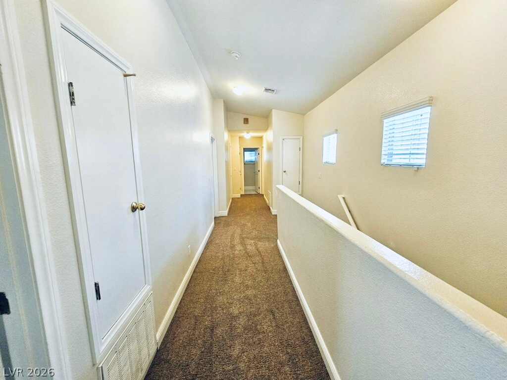 5953 Crumbling Ridge Street Henderson, NV 89011 - Photo 14 of 42 A well-lit hallway with textured walls and plush carpeting awaits.