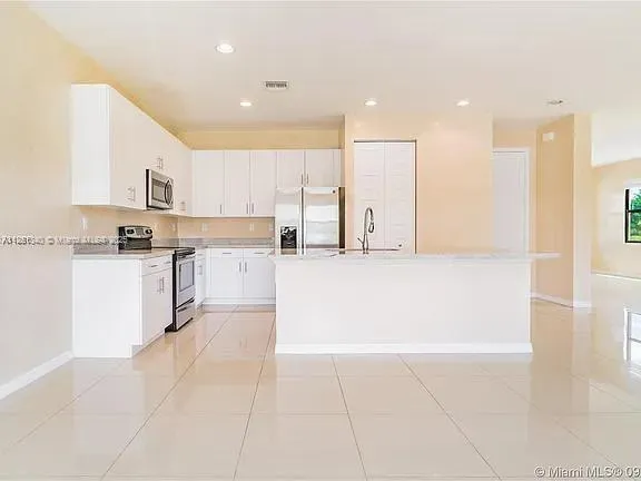 a kitchen with kitchen island white cabinets and stainless steel appliances