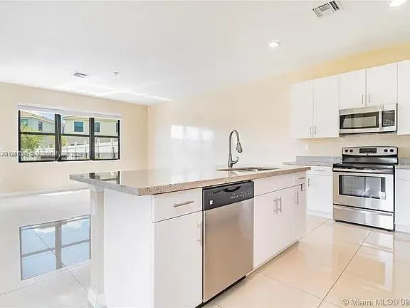 a kitchen with granite countertop a stove sink and microwave
