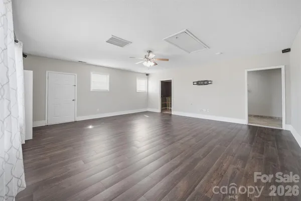 an empty room with wooden floor chandelier and windows