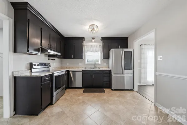a kitchen with stainless steel appliances granite countertop a refrigerator stove a sink dishwasher and wooden cabinets