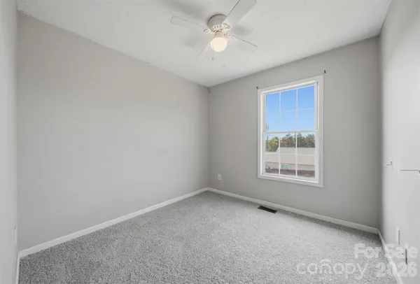 an empty room with a window and a fan