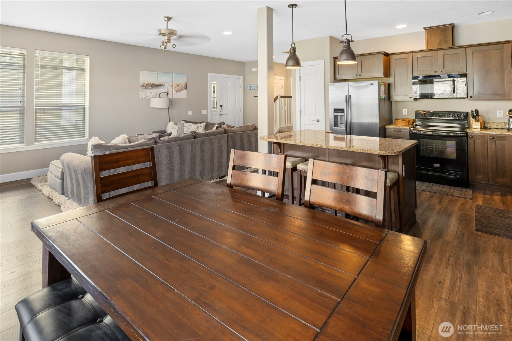 23041 Sunserra Loop Quincy, WA 98848 - Photo 12 of 38 a large kitchen with stainless steel appliances a stove a sink dishwasher a dining table and chairs with wooden floor
