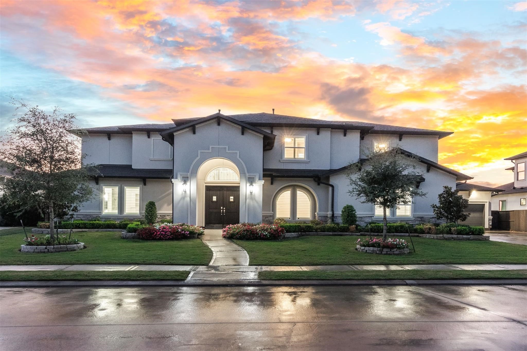 Striking stucco elevation with a grand arched entry and manicured landscaping creates impressive curb appeal and a welcoming first impression.
