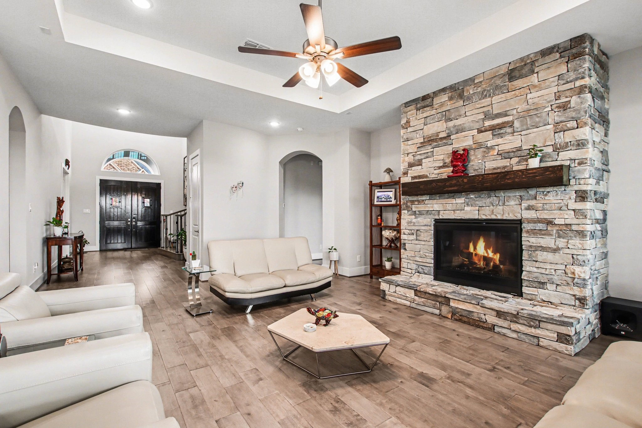 2311 Legends Way Katy, TX 77493 - Photo 12 of 50 Spacious family room featuring wood flooring, soaring ceilings, and a dramatic floor-to-ceiling stone fireplace that creates a stunning focal point.