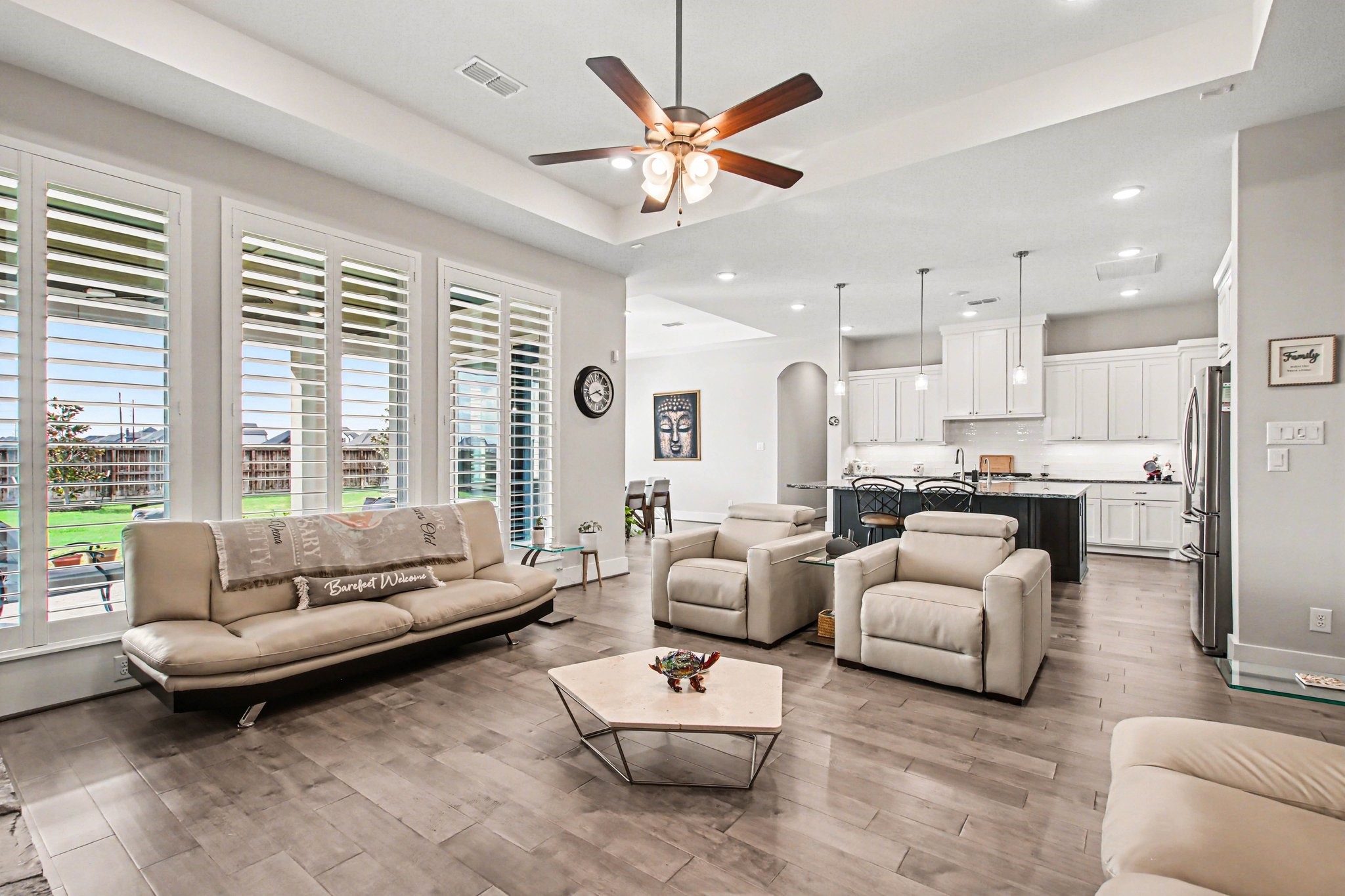 2311 Legends Way Katy, TX 77493 - Photo 14 of 50 Bright and inviting living space with large windows and plantation shutters overlooking the backyard, anchored by a beautiful stone fireplace and warm wood mantel—perfect for relaxing or entertaining.