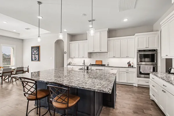 a kitchen with kitchen island granite countertop a table chairs stove microwave and refrigerator