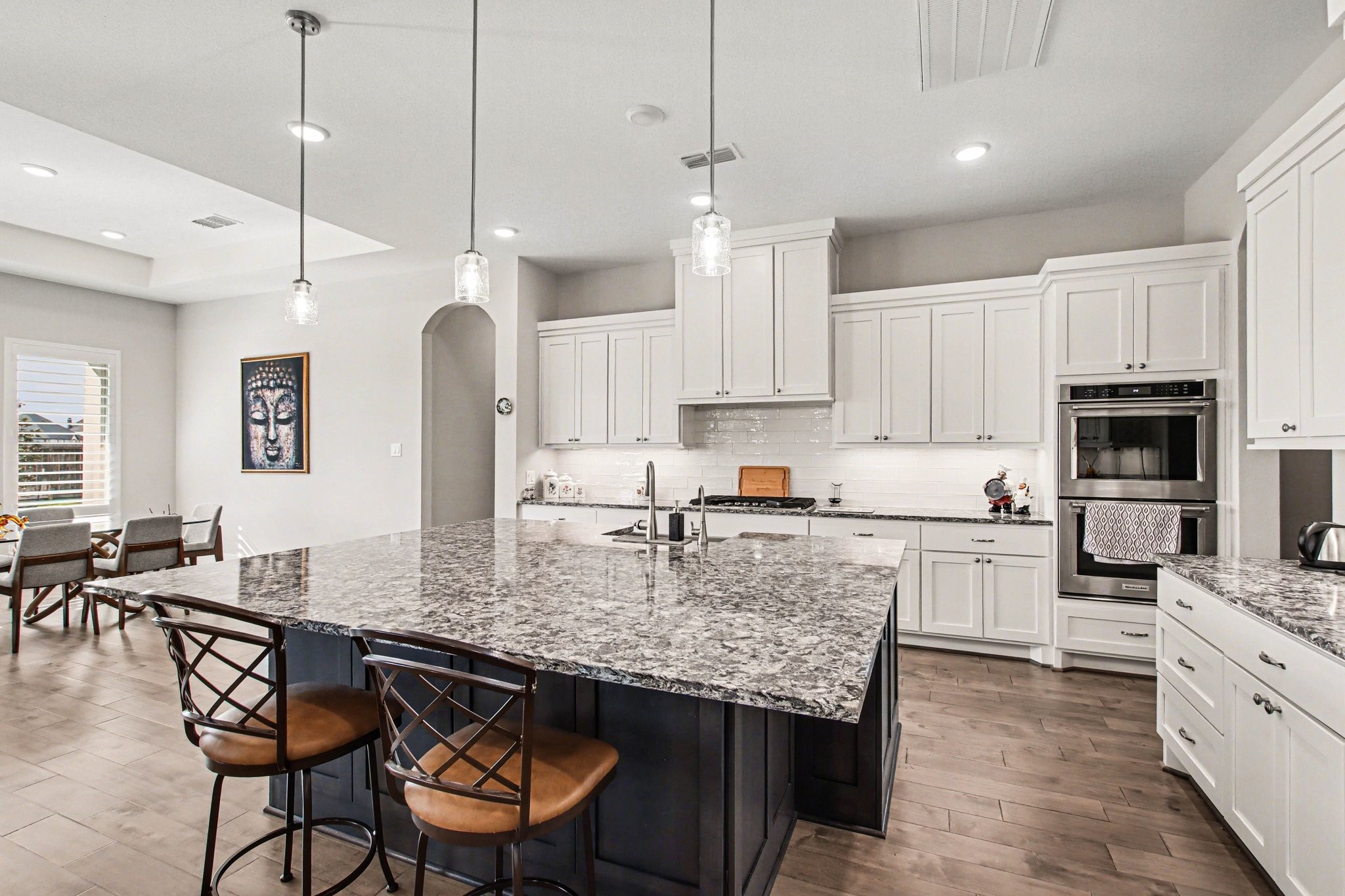 2311 Legends Way Katy, TX 77493 - Photo 17 of 50 A true chef’s kitchen designed to impress—featuring an oversized quartz island with contrasting cabinetry, custom white shaker cabinets, stainless steel appliances, and designer pendant lighting. The expansive layout offers abundant prep space and effortless entertaining.