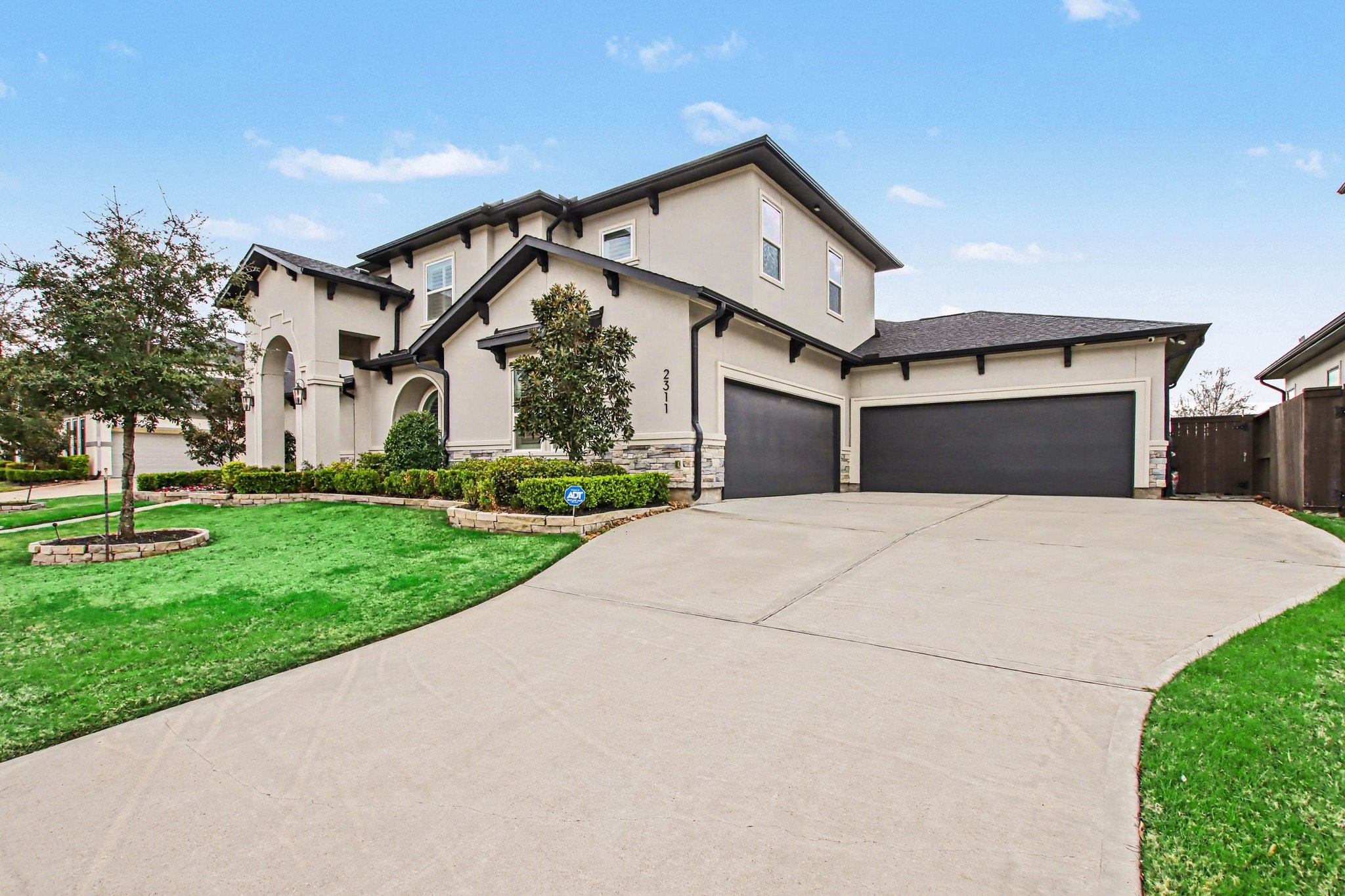 2311 Legends Way Katy, TX 77493 - Photo 2 of 50 Timeless design meets modern sophistication with a stately stucco façade, dramatic arched entryway, and lush, professionally landscaped yard. The expansive lawn and refined architectural lines set the tone for upscale living.