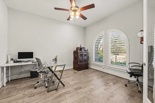 a bedroom with a bed next to a large window with wooden floor