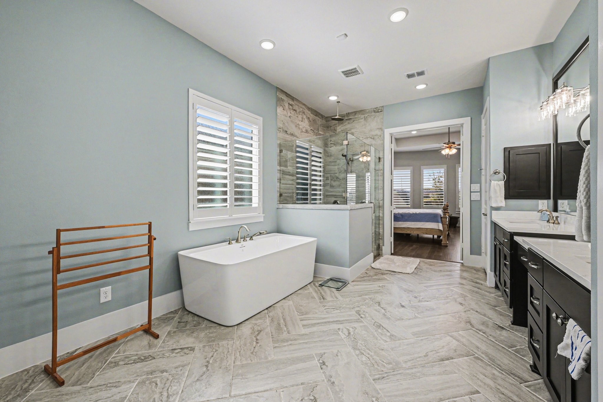 2311 Legends Way Katy, TX 77493 - Photo 32 of 50 Unwind in the freestanding soaking tub positioned beside plantation shutters for natural light and privacy. The glass-enclosed shower showcases beautiful tile work and upscale finishes for a true spa-like experience.