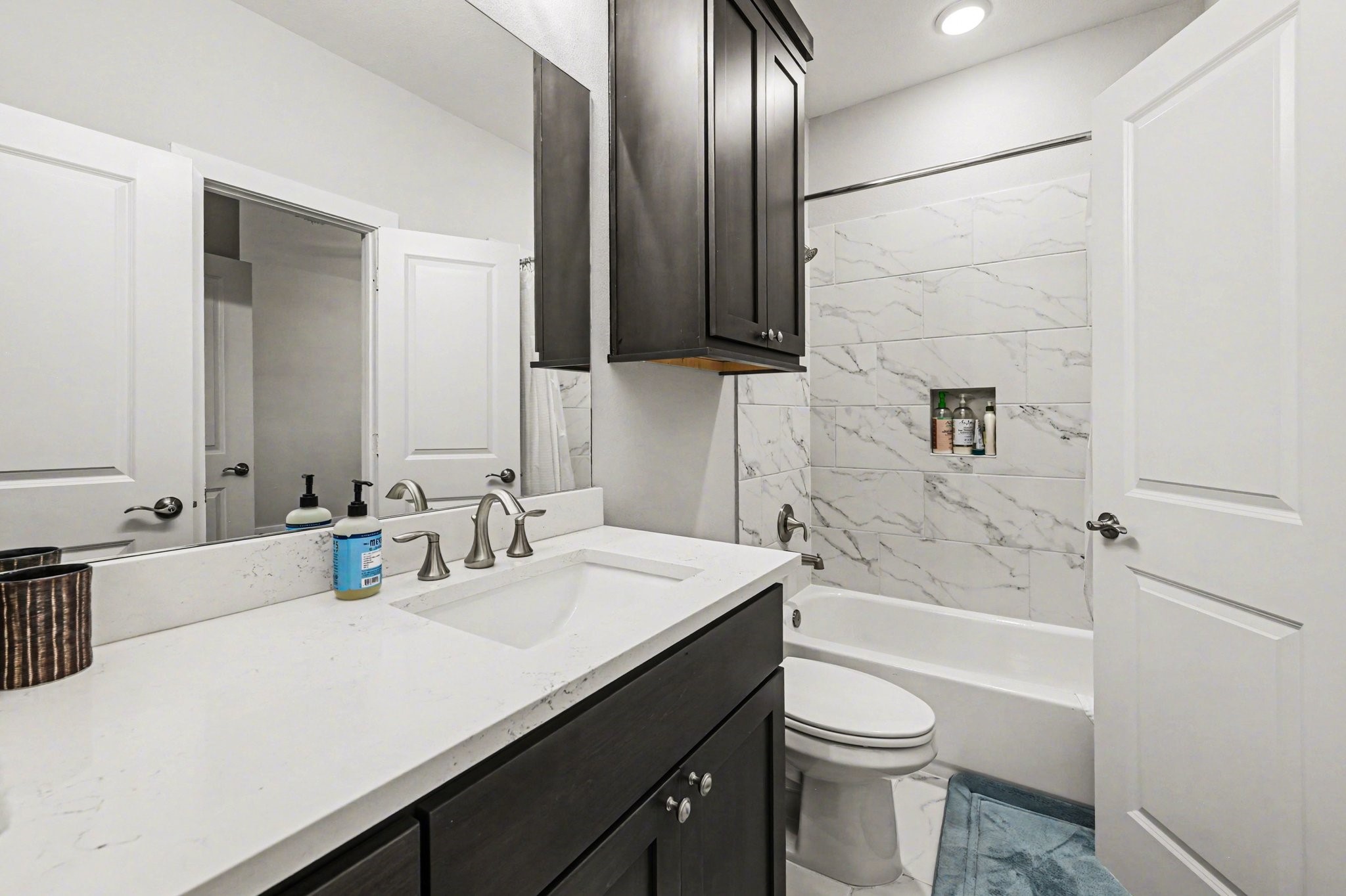 2311 Legends Way Katy, TX 77493 - Photo 40 of 50 Beautifully finished bath with marble-inspired tile surround, quartz countertops, and modern cabinetry—designed for everyday comfort with elevated style.