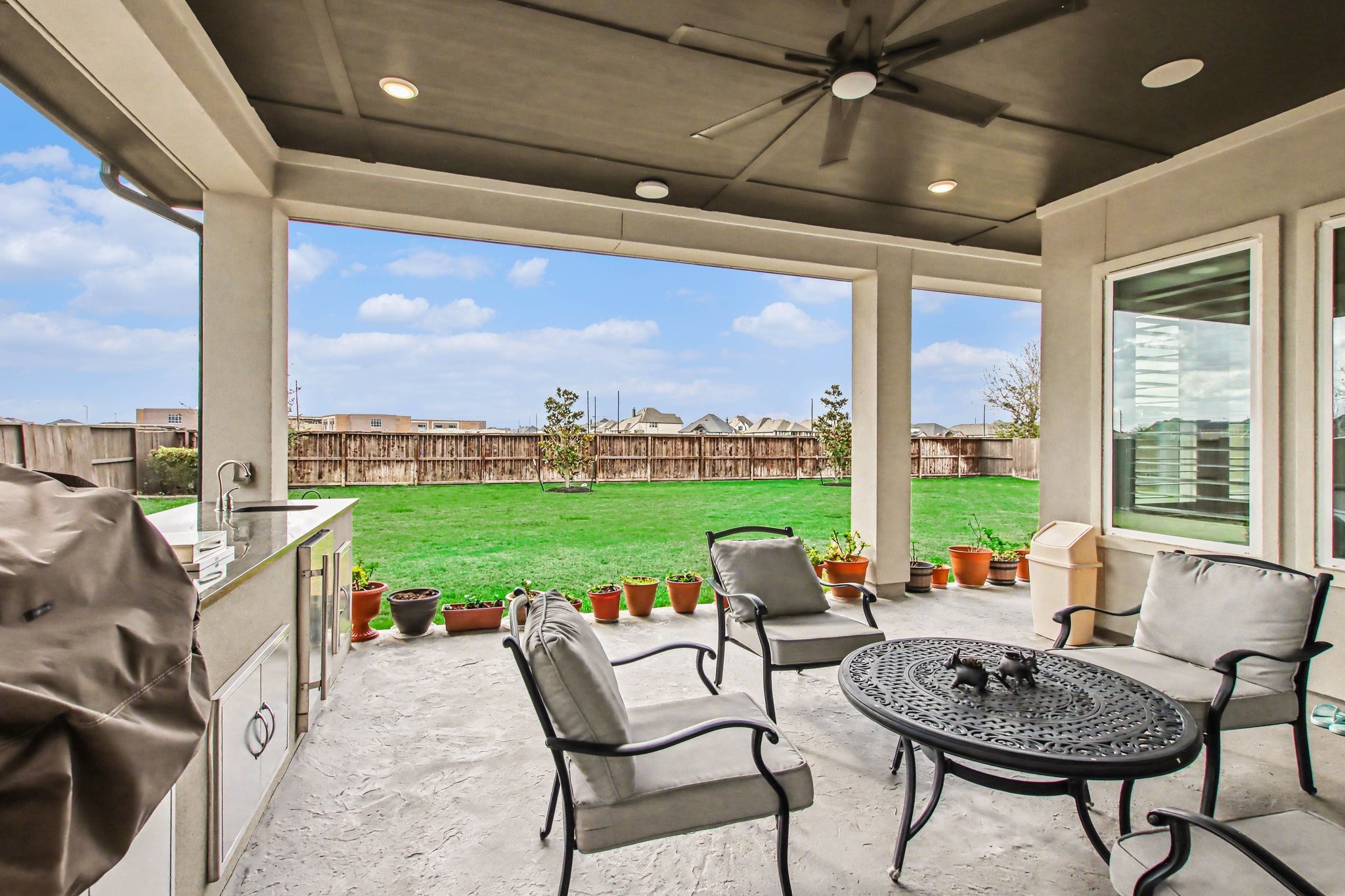 2311 Legends Way Katy, TX 77493 - Photo 46 of 50 Resort-style covered patio featuring a full outdoor kitchen with built-in grill, sink, and refrigerator—perfect for year-round entertaining. The extended covered ceiling and recessed lighting create a true outdoor living experience.