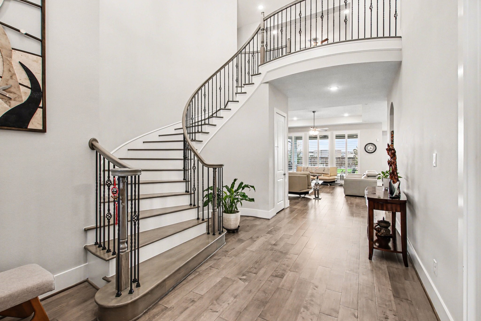 2311 Legends Way Katy, TX 77493 - Photo 6 of 50 Step into a breathtaking two-story foyer featuring a sweeping curved staircase with wrought-iron balusters and wood accents. Wide-plank flooring and soaring ceilings set a luxurious tone from the moment you enter.