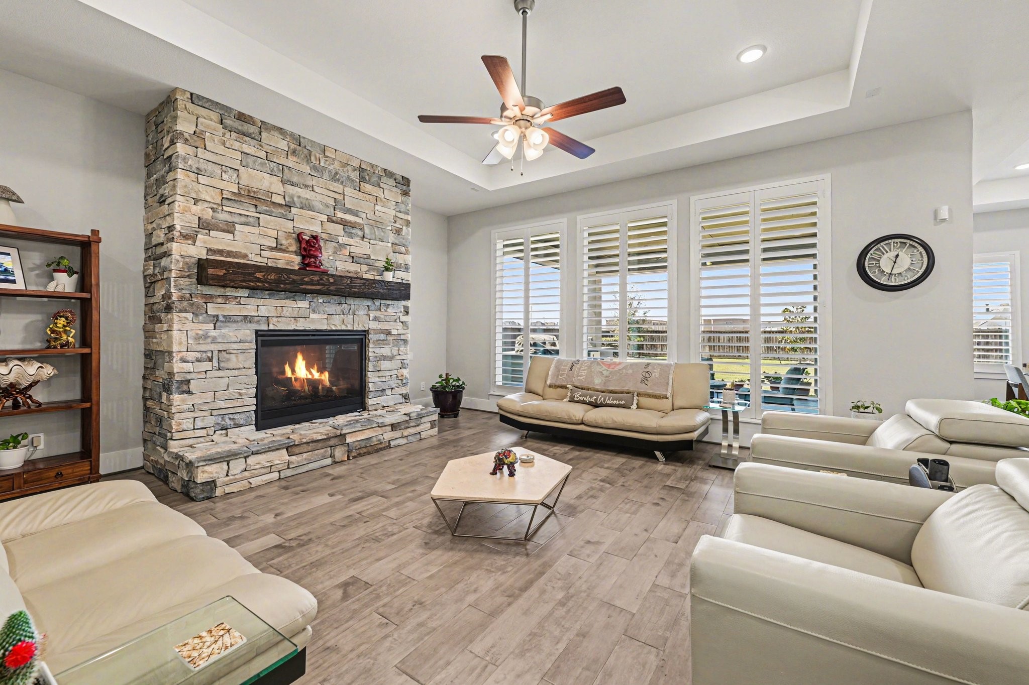 2311 Legends Way Katy, TX 77493 - Photo 9 of 50 The spacious family room is anchored by a floor-to-ceiling stone fireplace with a rustic wood mantel—an inviting focal point for gatherings. Expansive windows with plantation shutters flood the space with natural light.