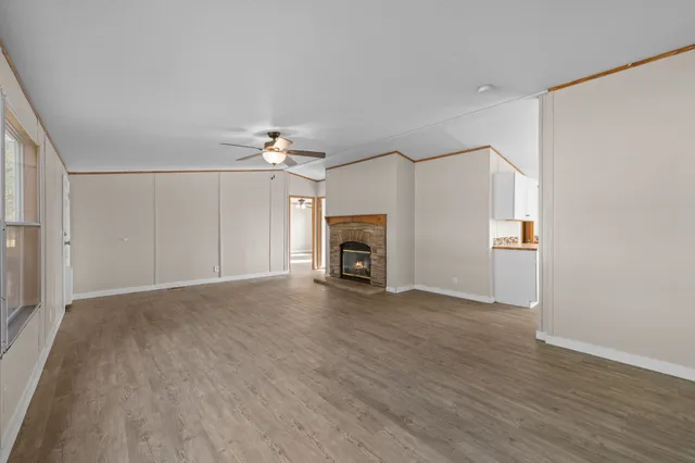 an empty room with wooden floor fireplace and windows