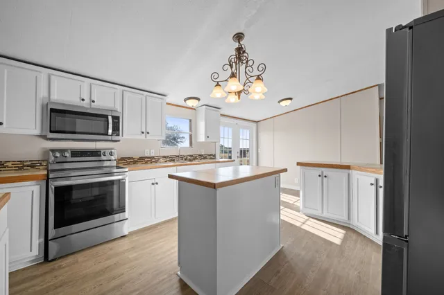 a kitchen with kitchen island granite countertop a sink cabinets and stainless steel appliances