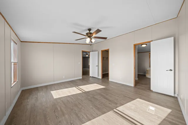an empty room with wooden floor and ceiling fan
