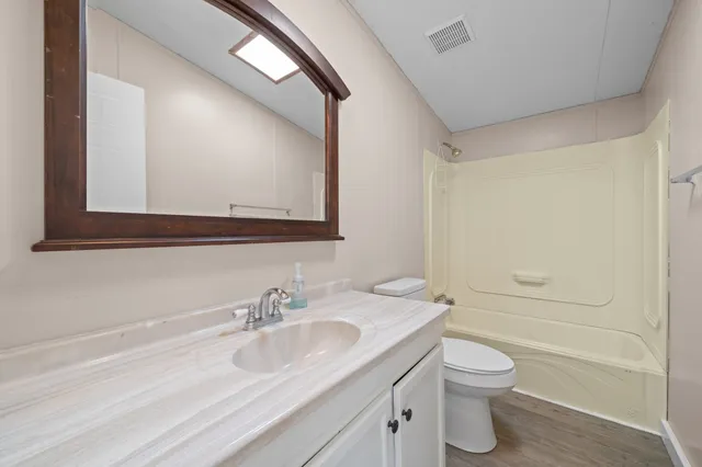 a bathroom with a granite countertop sink toilet and a mirror