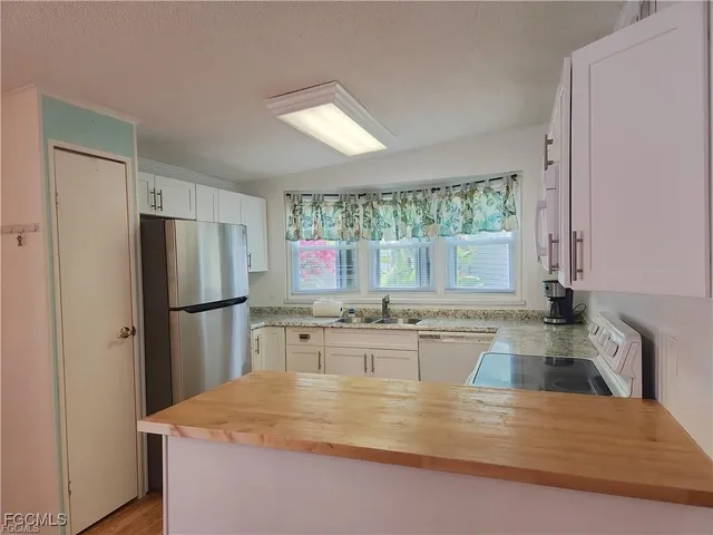 a kitchen with kitchen island a refrigerator a stove a sink cabinets and a large window