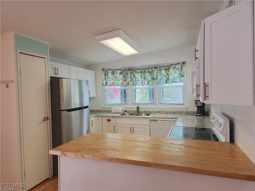 10401 Circle Pine Road North Fort Myers, FL 33903 - Photo 6 of 20 a kitchen with kitchen island a refrigerator a stove a sink cabinets and a large window