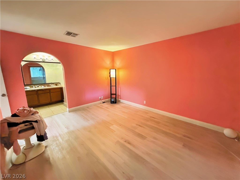 1852 North Decatur Boulevard, Unit 101 Las Vegas, NV 89108 - Photo 9 of 45 An arched doorway leads to the adjacent bathroom from this spacious bedroom featuring wood flooring.