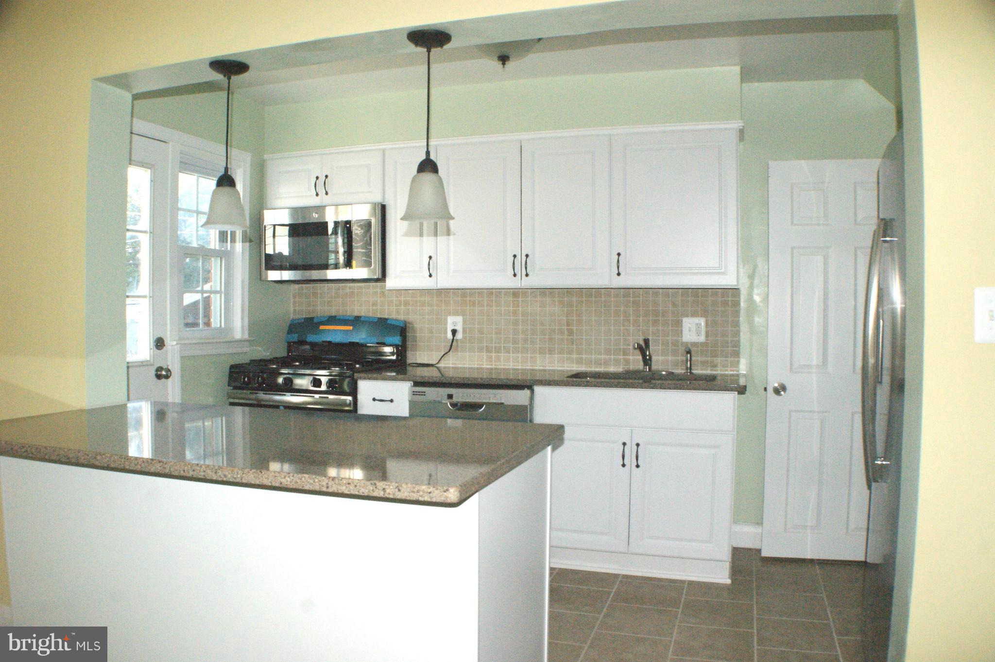1917 Nevill Road Baltimore, MD 21222 - Photo 3 of 23 a kitchen with stainless steel appliances granite countertop a sink a refrigerator and white cabinets