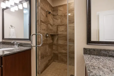 a bathroom with a granite countertop sink a mirror and shower