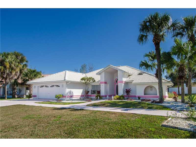 a view of a white house with a big yard plants and large trees