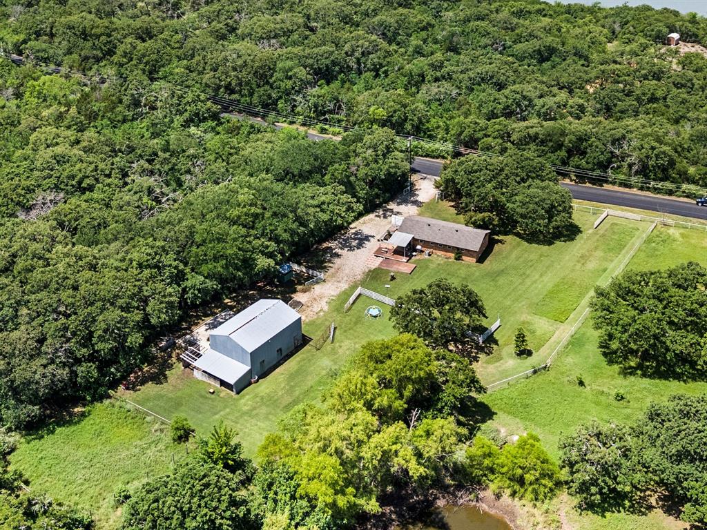 3900 Moseley Road Cross Roads, TX 76227 - Photo 35 of 36 Expansive property featuring a single-story residence, a large metal-sided outbuilding, mature trees, and a natural pond