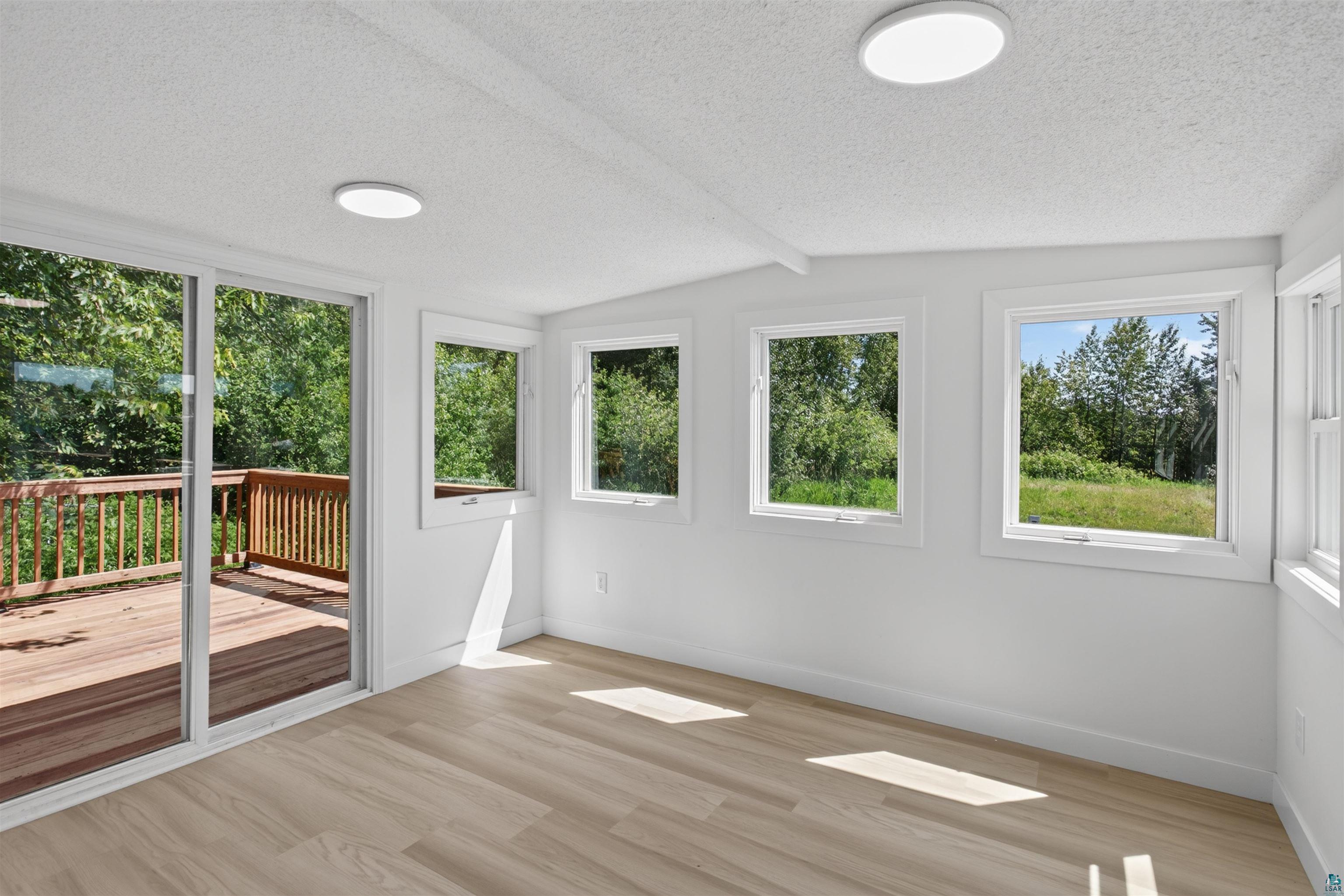 5868 Rice Lake Road Duluth, MN 55803 - Photo 18 of 39 Interior room featuring light wood-finish flooring, white walls, and multiple windows