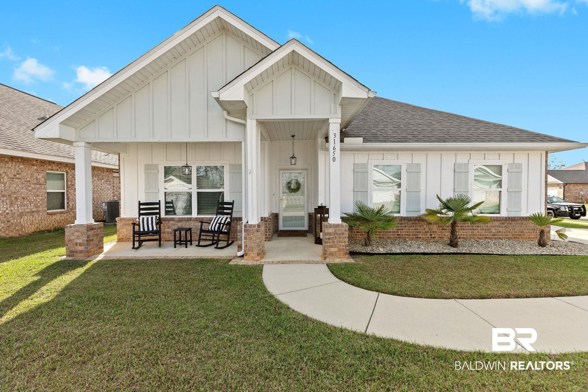 31650 Memphis Loop Daphne, AL 36527 - Photo 1 of 68 View of front of property with board and batten siding, a front yard, brick siding, covered porch, and a shingled roof