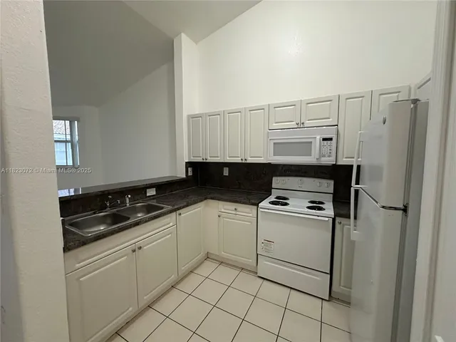 a kitchen with white cabinets and white appliances