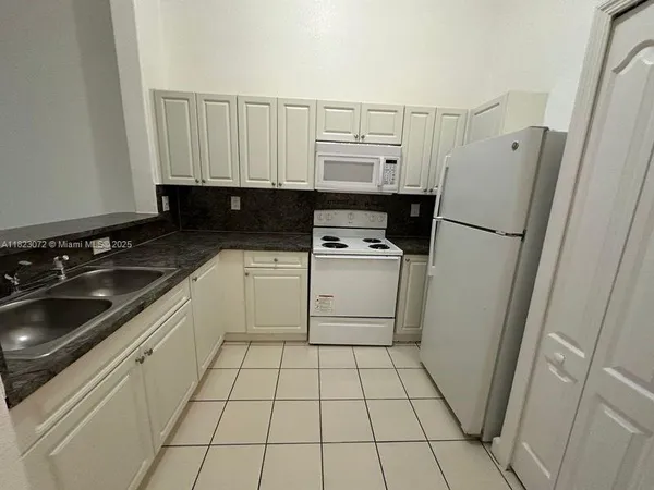 a kitchen with granite countertop white cabinets and sink