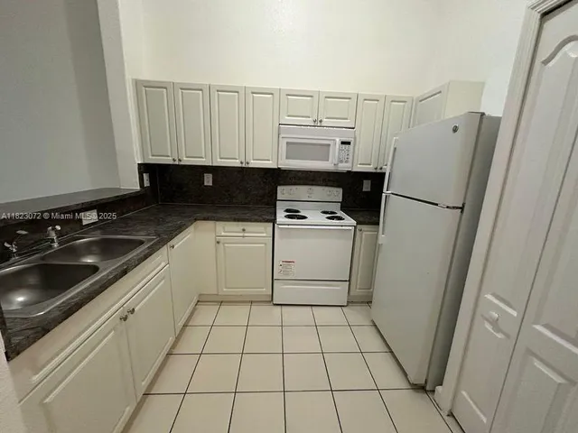 a kitchen with granite countertop white cabinets and sink