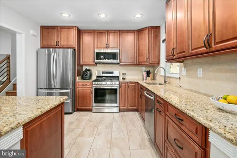 a kitchen with stainless steel appliances granite countertop wooden cabinets a sink and a stove