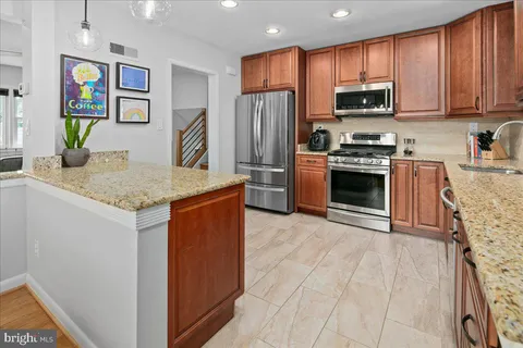 a kitchen with stainless steel appliances granite countertop a refrigerator and a stove top oven