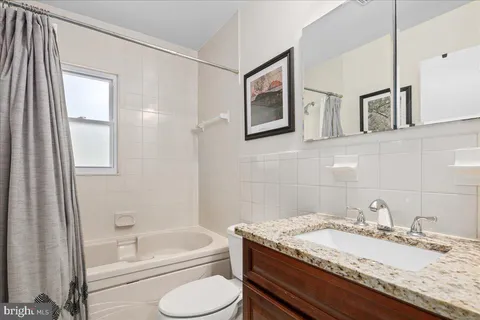a bathroom with a granite countertop sink toilet and a mirror