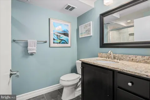 a bathroom with a granite countertop toilet sink and mirror