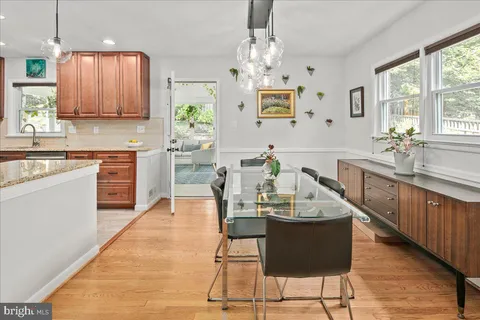 a kitchen with stainless steel appliances granite countertop wooden cabinets a stove a sink a dining table and chairs