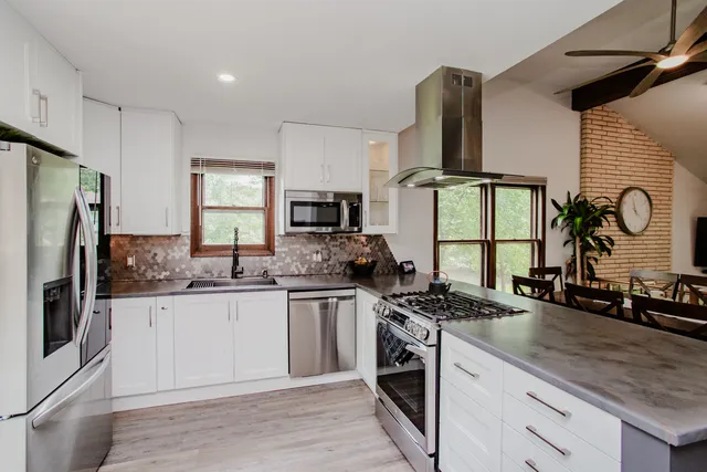 a kitchen with stainless steel appliances granite countertop a sink stove refrigerator and cabinets