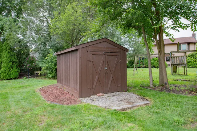 a view of a tiny house with a small yard and large trees