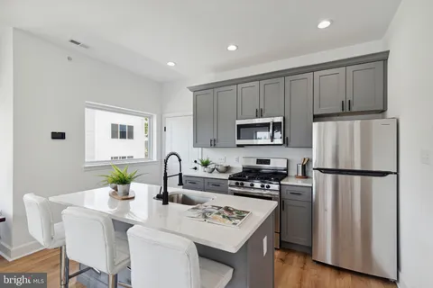a kitchen with stainless steel appliances granite countertop a refrigerator a stove a sink a dining table and chairs