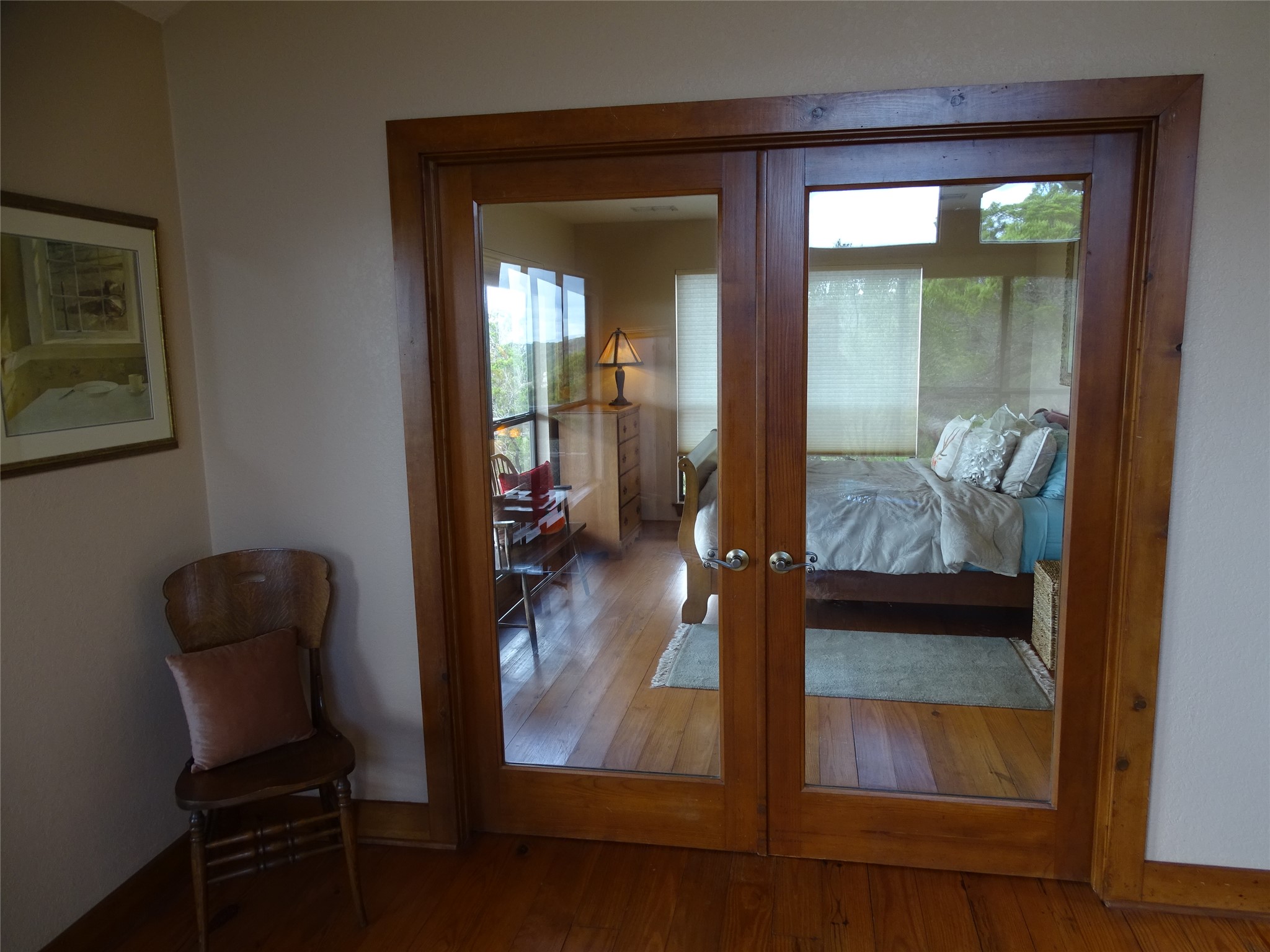 919 Little Ranches Road Wimberley, TX 78676 - Photo 8 of 13 Solid wood French doors lead to a serene bedroom featuring hardwood floors and ample natural light.
