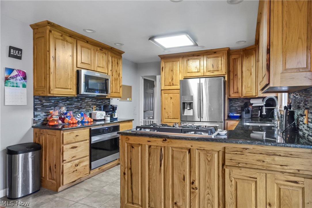 346 Amboy Road Conneaut, OH 44030 - Photo 14 of 41 Kitchen featuring tasteful backsplash, stainless steel appliances, kitchen peninsula, and light tile floors