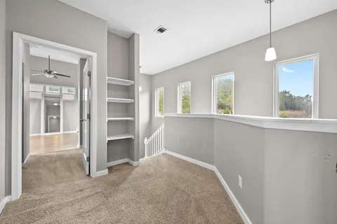 a view of an empty room with a window and a kitchen